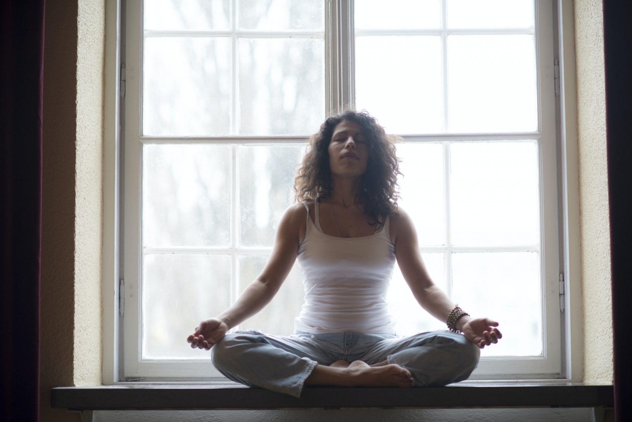 woman meditating in front of a window