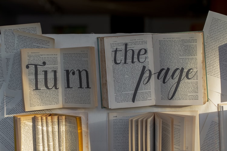 open book with black lettering that reads "turn the page"