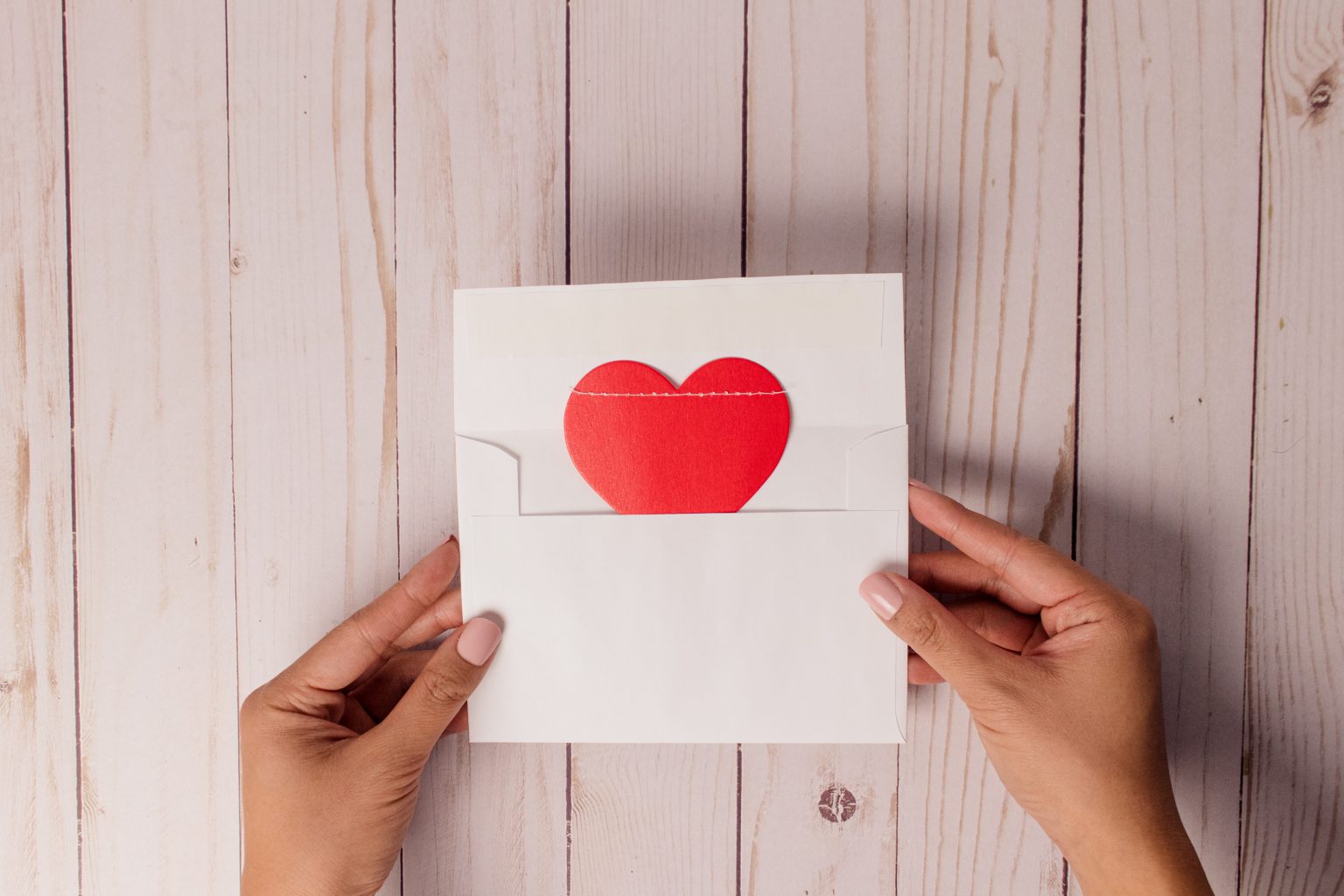 hands holding a card with a red heart on it