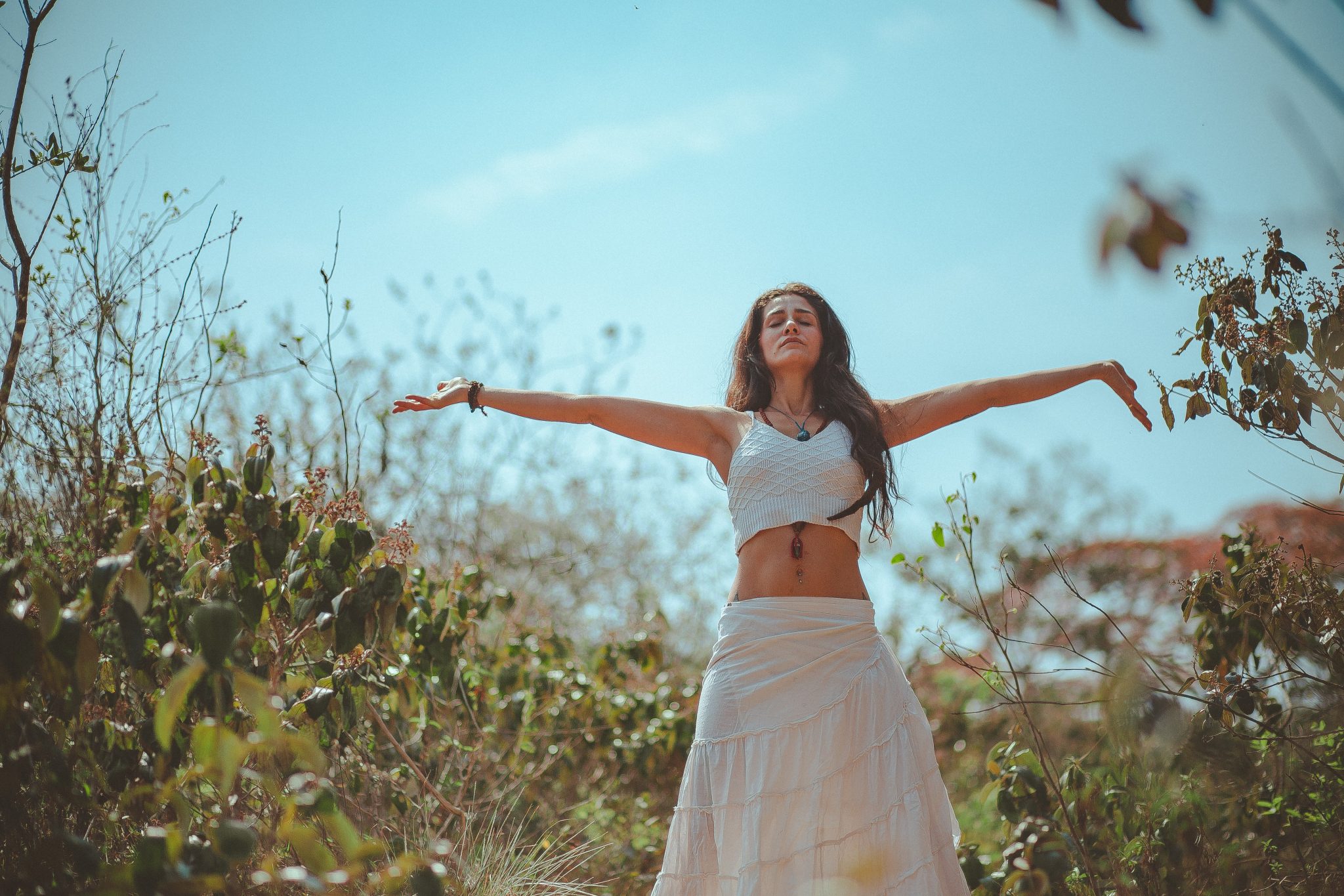woman meditating in a field with her arms outstretched