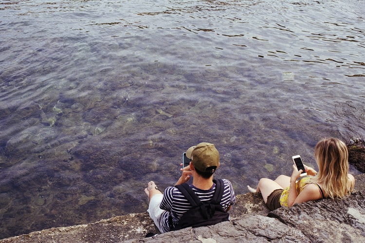 people on phones in front of water