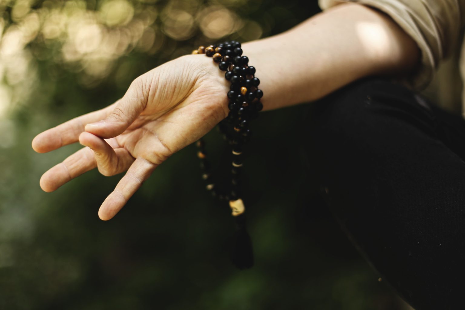 hand of meditator with beaded bracelet