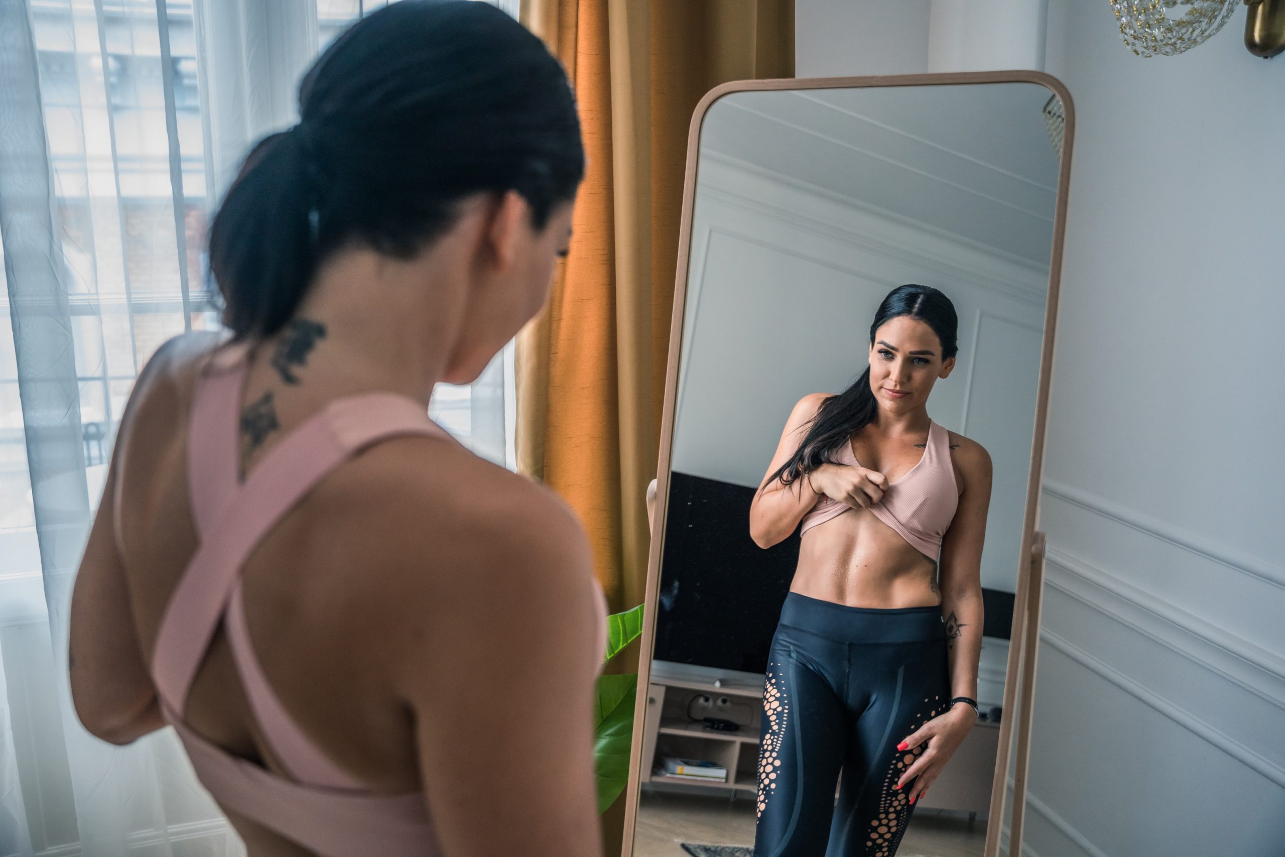 woman looking at her abs in a mirror