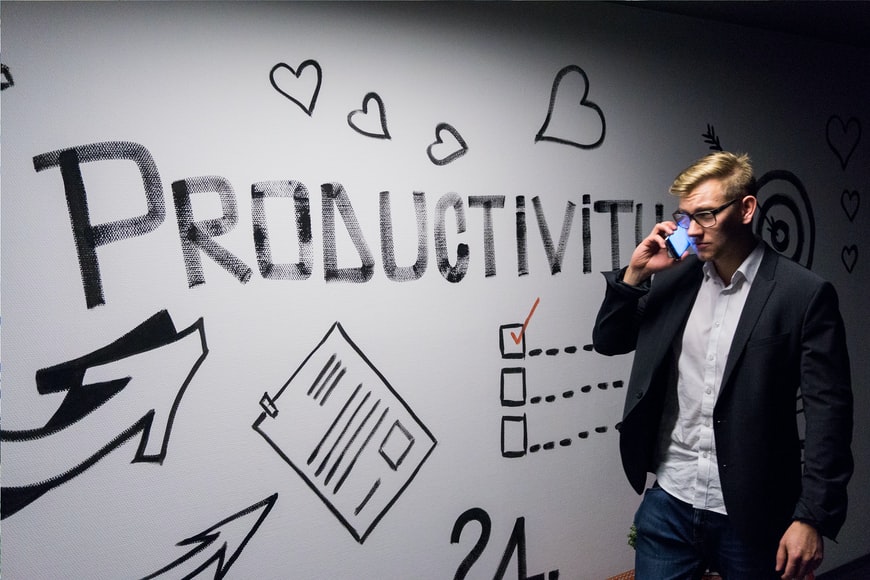 man on the phone in front of wall that reads "productivity"