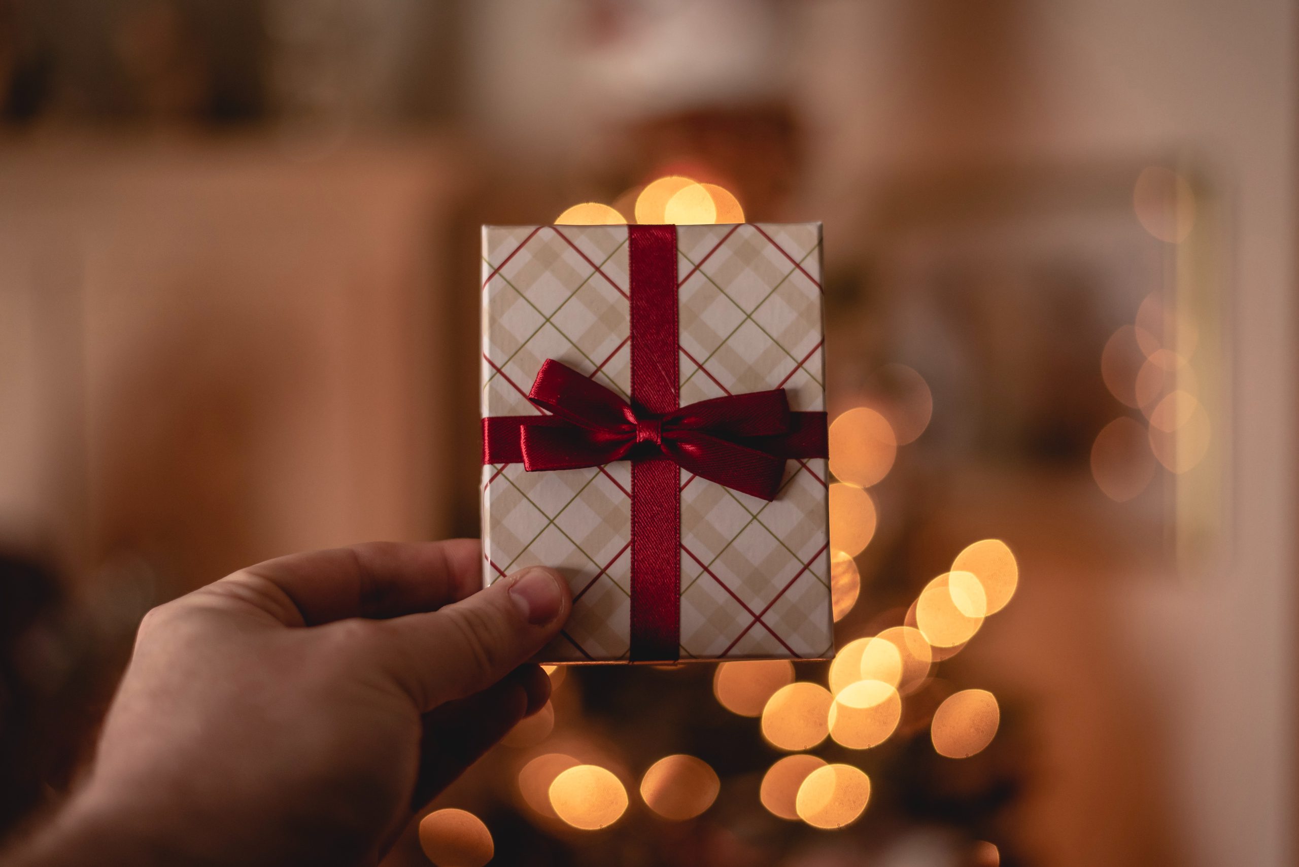 hand holding a wrapped gift card with red bow