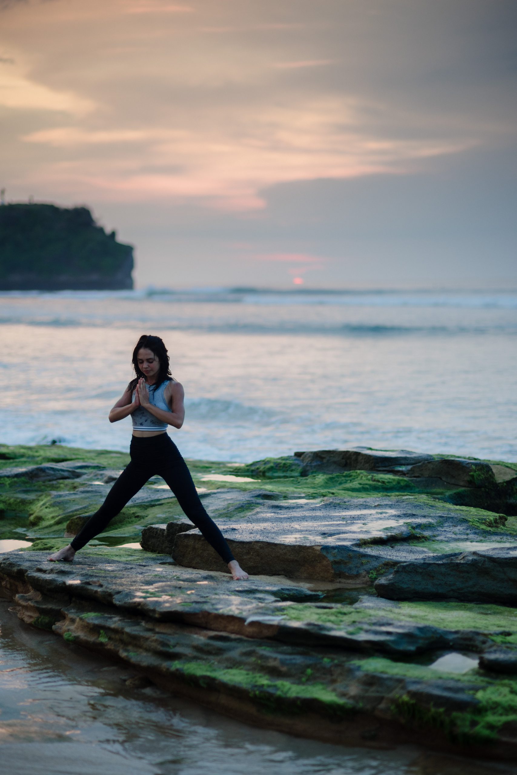 woman doing yoga on a rocky beach