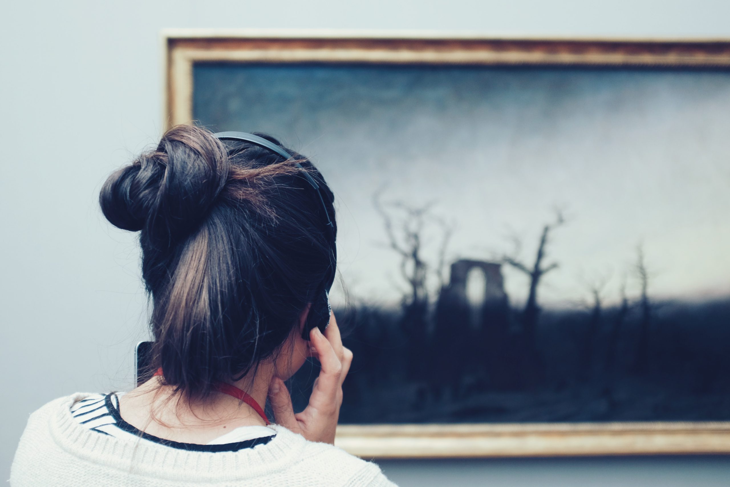 woman listening to guide while looking at a painting