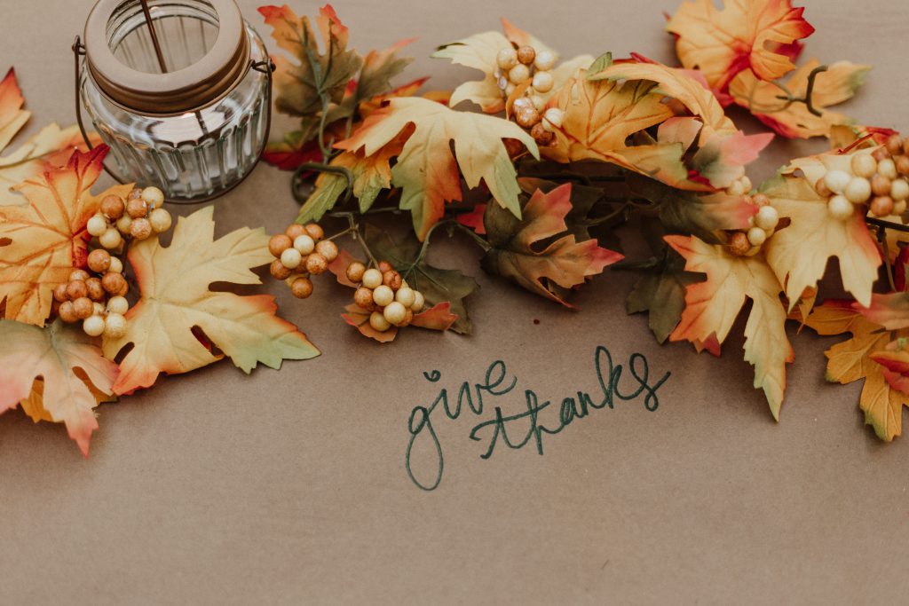 give thanks written on brown paper surrounded by fall leaves