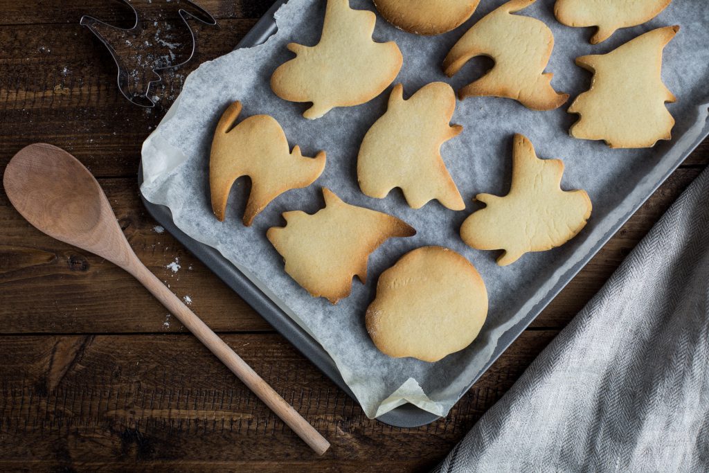 baking sheet with cookies in the shape of ghosts and cats