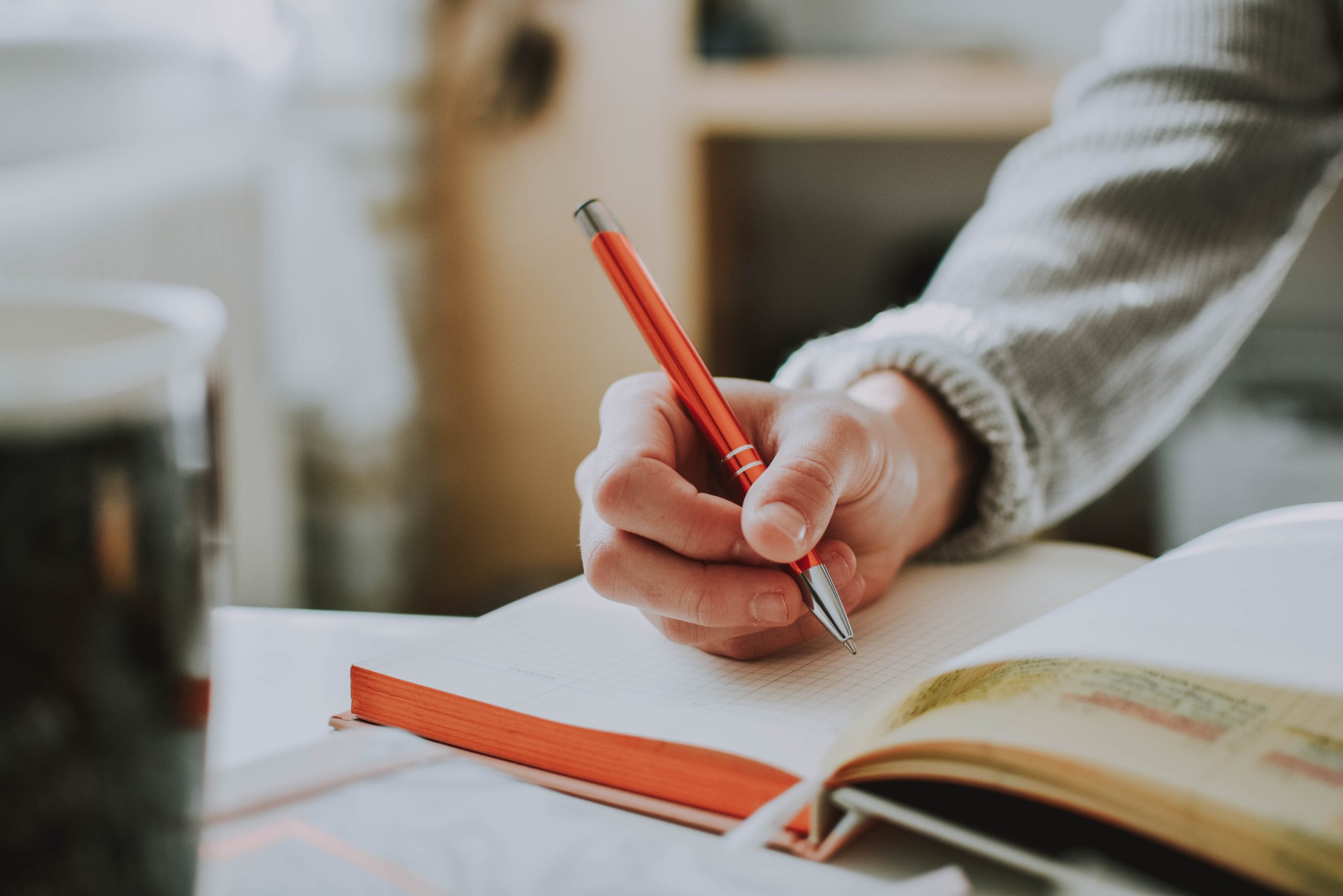 woman writing in a notebook with orange pen