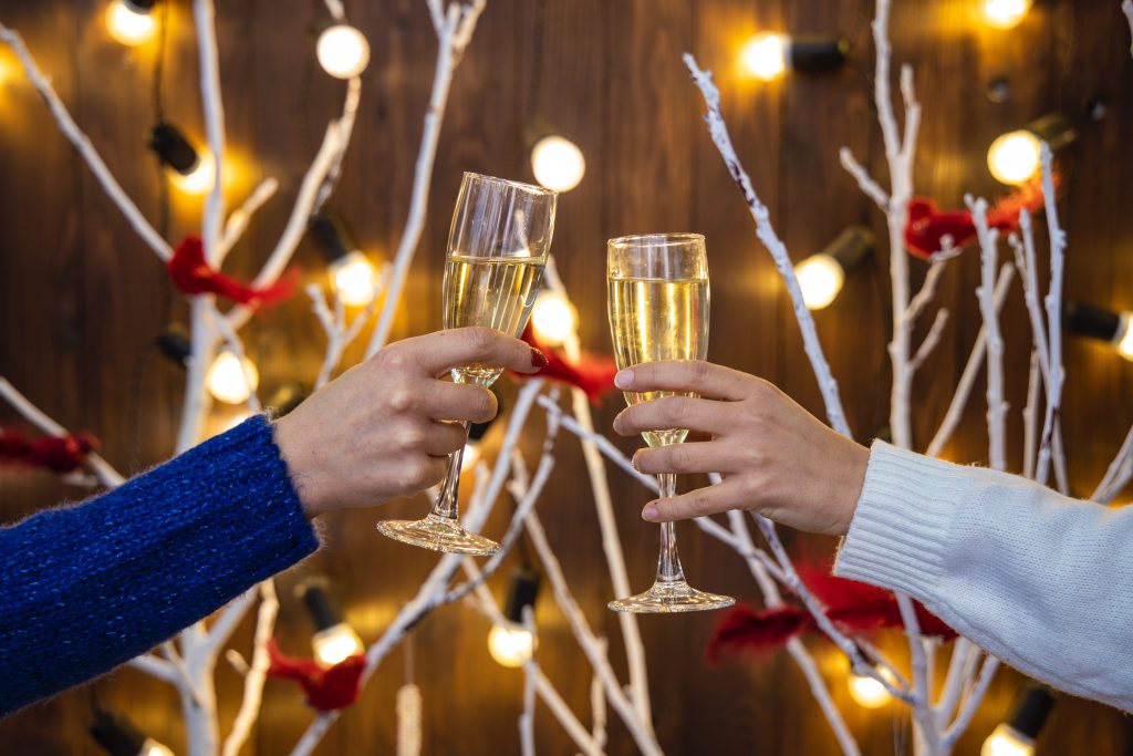 two people clinking champagne glasses at a holiday party