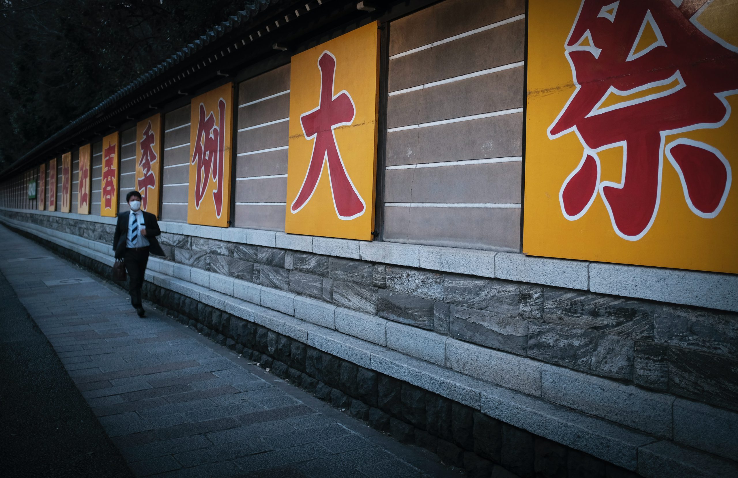 man walking down a path with yellow japanese signs
