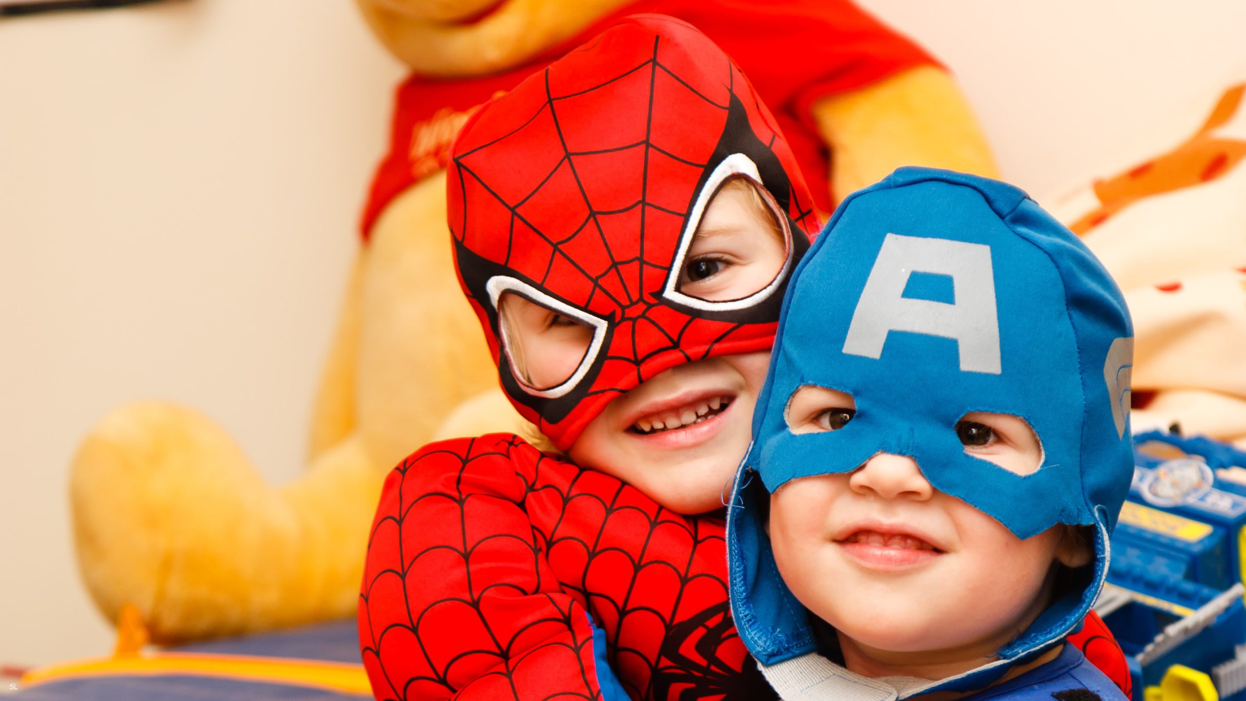 two boys hugging, dressed as spiderman and captain america