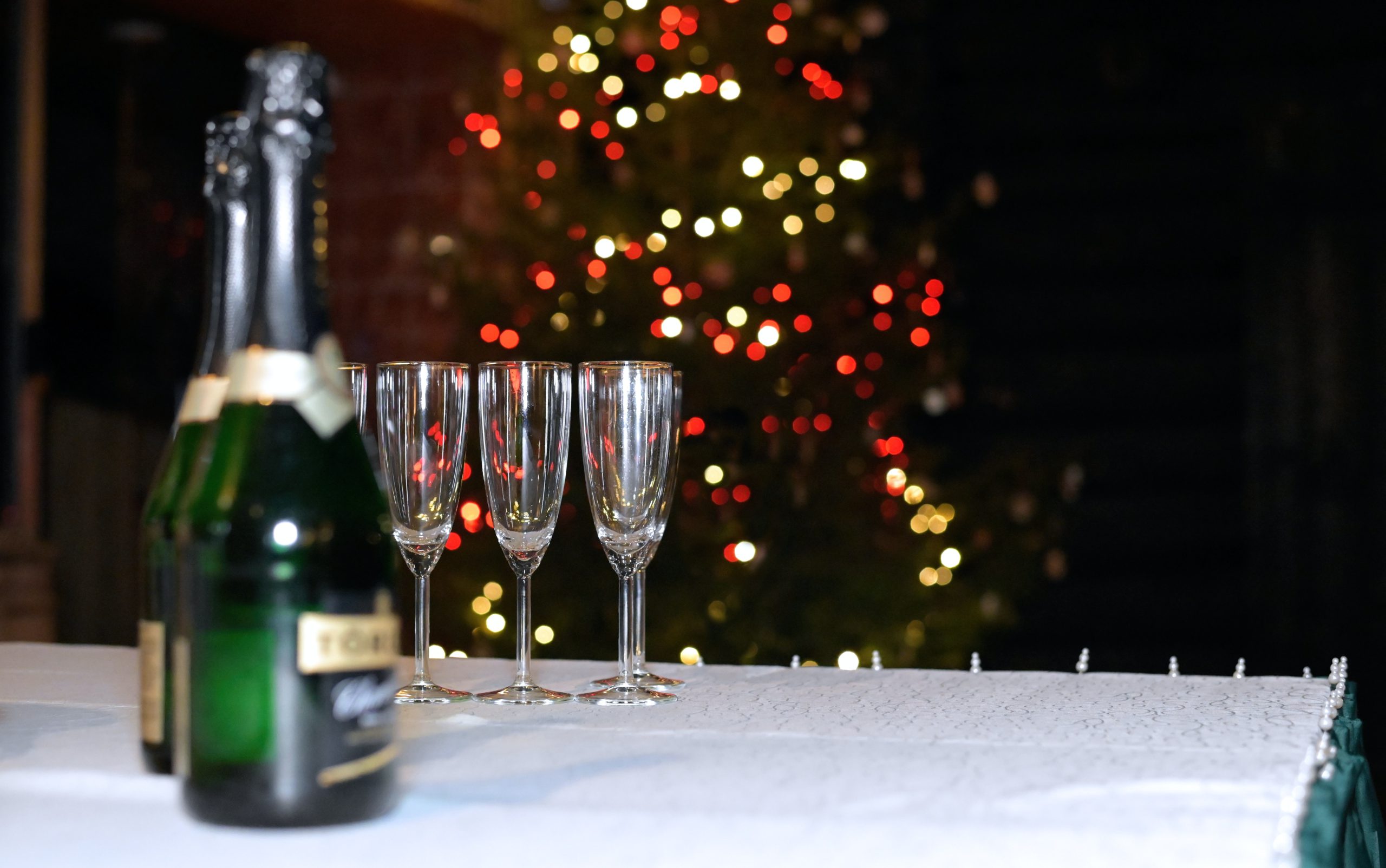 champagne bottles and glasses in front of a christmas tree